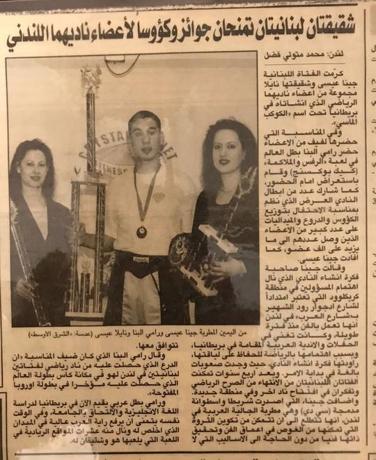 An Arabic newspaper cutting from London about two Lebanese sisters presenting awards and trophies to members of their London club, with a medal winner photographed between them.