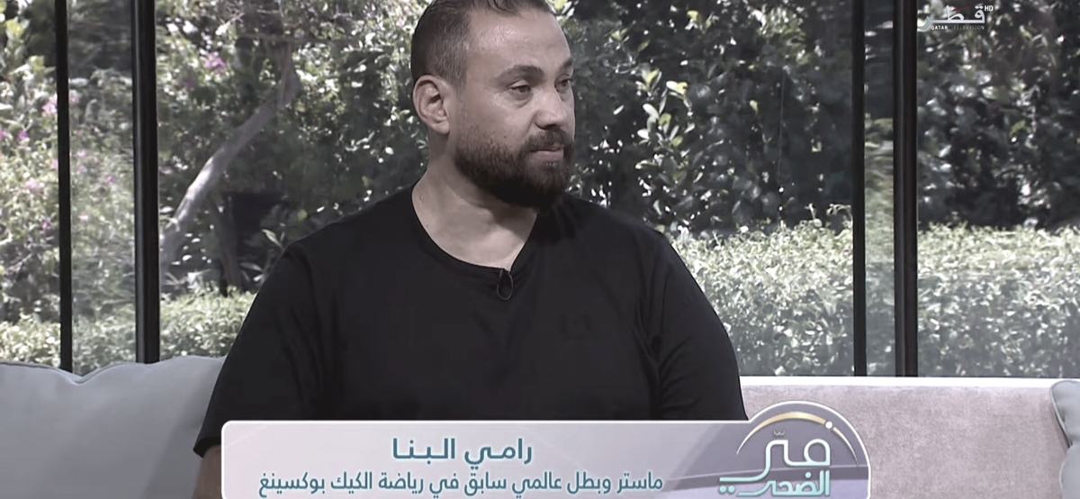 A television still of Master Rami Al Banna mid interview, a lower third reading his name and his title as a master and former world champion in kickboxing.